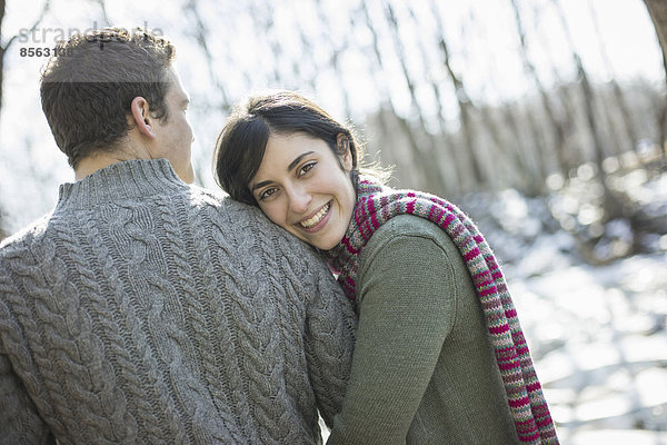 Zwei Personen  ein Paar an einem Wintertag im Freien. Einander umarmend.