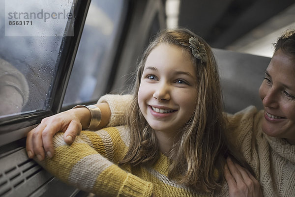 Ein Mann und ein junges Mädchen sitzen in einem Zugwaggon am Fenster und blicken auf die Landschaft. Lächeln vor Aufregung.