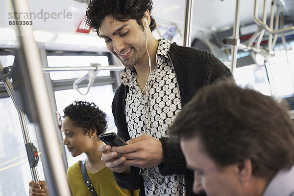 New Yorker Stadtpark. Menschen  Männer und Frauen in einem Stadtbus. Öffentliche Verkehrsmittel. In Kontakt bleiben. Ein junger Mann  der sein Mobiltelefon überprüft.
