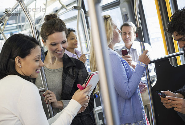 New Yorker Stadtpark. Menschen  Männer und Frauen in einem Stadtbus. Öffentliche Verkehrsmittel. Zwei Frauen betrachten ein tragbares digitales Tablet.
