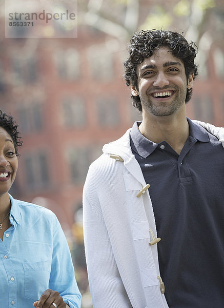 Menschen im Frühling in der Stadt im Freien. Der New Yorker Stadtpark. Ein Mann und eine Frau Seite an Seite  lächelnd.