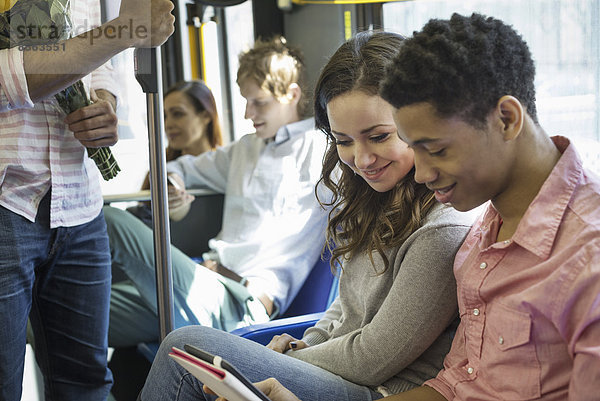 Urbaner Lebensstil. Eine Gruppe von Menschen  Männer und Frauen  in einem Stadtbus in New York City. Ein Paar nebeneinander  das auf ein digitales Tablet schaut.