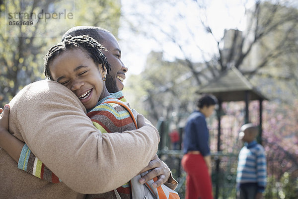 Ein New Yorker Stadtpark im Frühling. Eine Familie zusammen. Ein Vater umarmt seinen Sohn.