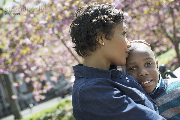 Ein New Yorker Stadtpark im Frühling. Sonnenschein und Kirschblüte. Eine Mutter und ihr Sohn verbringen Zeit miteinander.