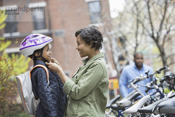 Ein New Yorker Stadtpark im Frühling. Ein Junge mit einem Fahrradhelm  der von seiner Mutter neben einem Fahrradträger befestigt wird.