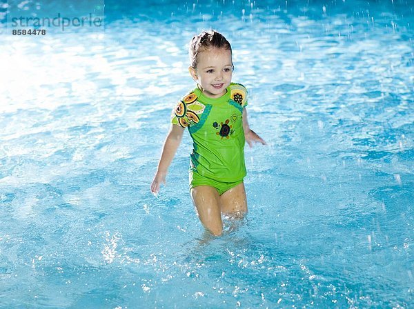 Kleines Mädchen spritzt Wasser am Swimmingpool