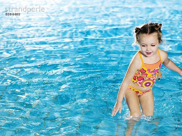 Kleines Mädchen spielt im Wasser am Swimmingpool