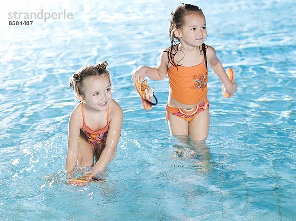 Zwei lächelnde Mädchen am Swimmingpool