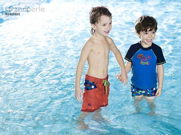 Zwei Jungen  die sich im Schwimmbad mit den Händen im Wasser bewegen.