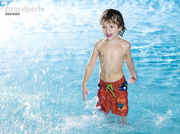 Junge spielt mit Wasser im Schwimmbad