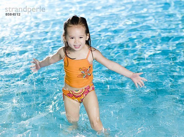 Kleines Mädchen spielt mit Wasser am Swimmingpool