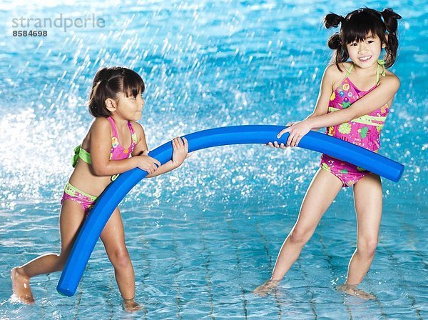 Zwei Mädchen spielen mit Poolnudeln