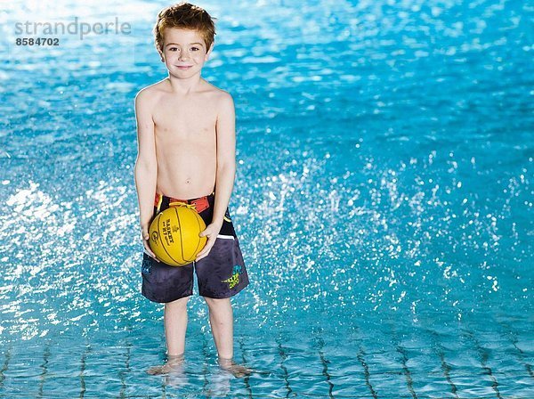 Kleiner Junge mit Ball im Schwimmbad