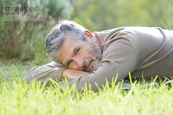 Erwachsener Mann  der auf dem Rasen liegt.