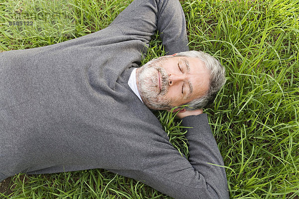 Erwachsener Mann  der auf dem Rasen liegt.