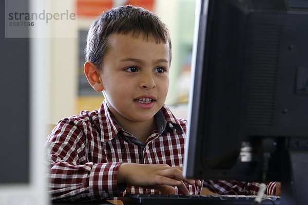 7-jähriger Junge  der einen Computer benutzt. Frankreich.