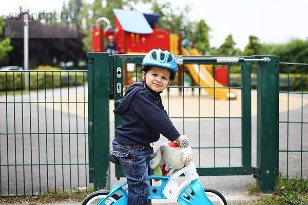 Ein kleiner Junge und sein Fahrrad kommen im Park an.