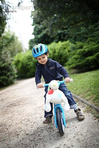 Ein kleiner Junge und sein Fahrrad im Park