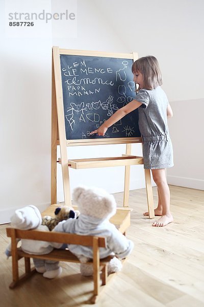 Ein kleines Mädchen spielt die Lehrerin mit ihren Kuscheltieren.