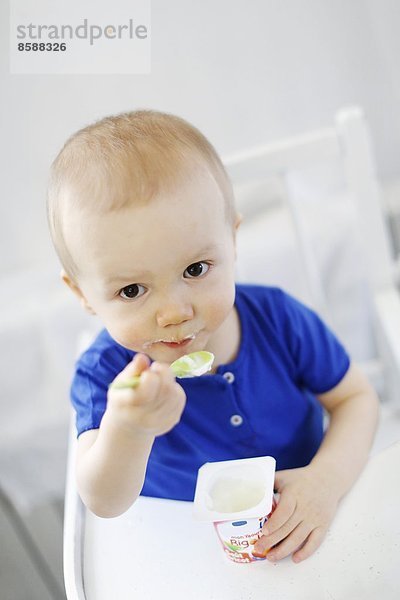 Ein kleiner Junge isst Joghurt.