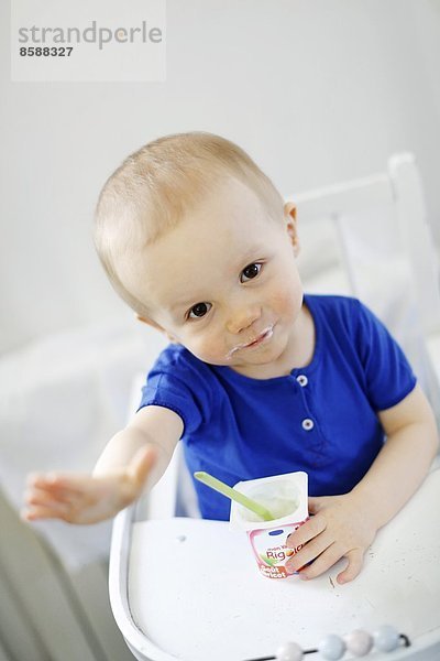 Ein kleiner Junge isst Joghurt.