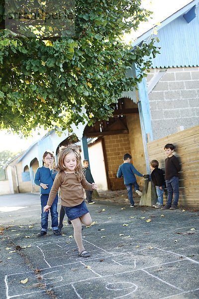 Mädchen spielen Hopscotch auf dem Schulhof