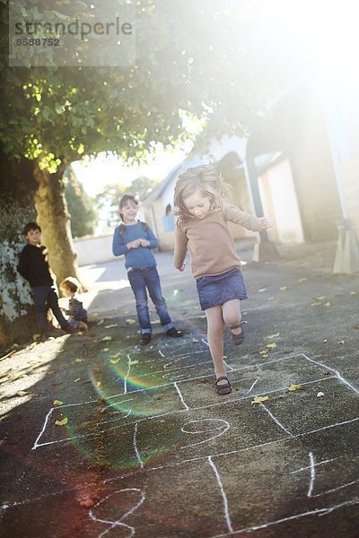 Mädchen spielen Hopscotch auf dem Schulhof