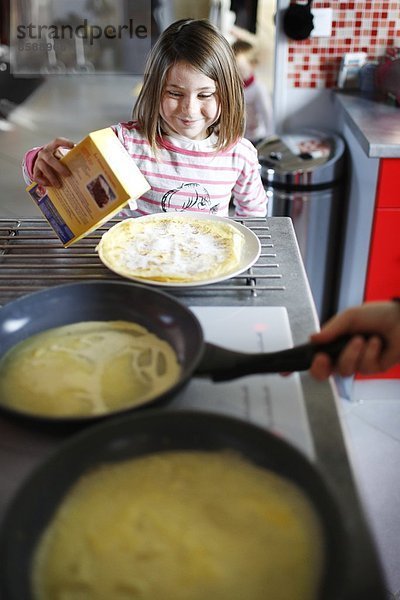 Ein kleines Mädchen macht Crêpes.