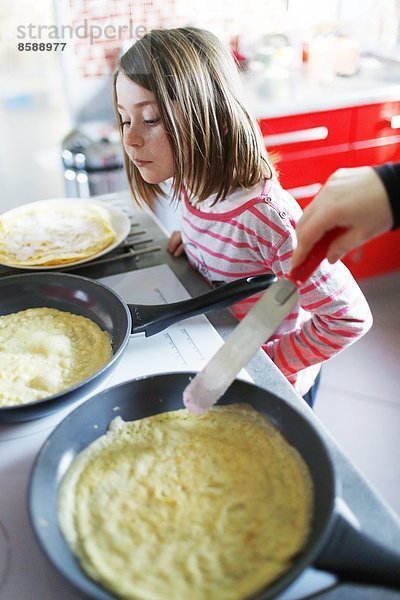 Ein kleines Mädchen macht Crêpes.