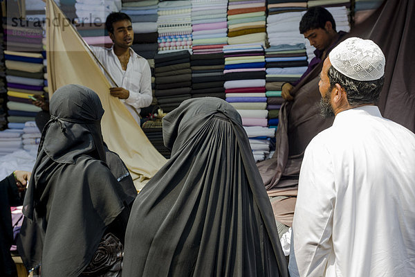 Zwei muslimische Frauen und ein Mann kaufen Stoff auf dem Mangaldas Market  Mumbai  Maharashtra  Indien
