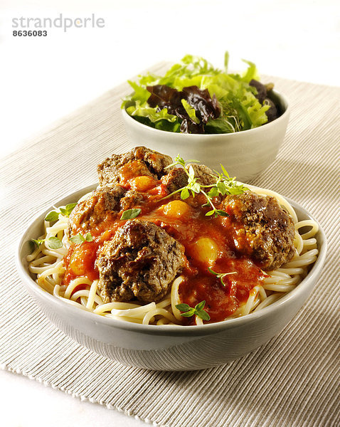 Hackfleischbällchen auf Spaghetti mit einer Sauce aus Tomaten  Basilikum und Schalotten  mit einem grünen Salat
