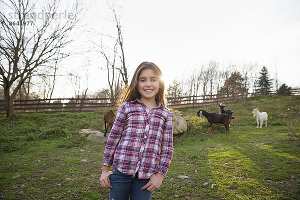 Ein Kind  ein junges Mädchen im Gehege der Ziegenkoppel in einem Tierschutzgebiet.