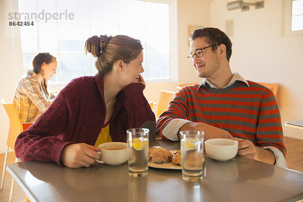 Zwei junge Leute  ein Mann und eine junge Frau  sitzen an einem Tresen in einem Café.