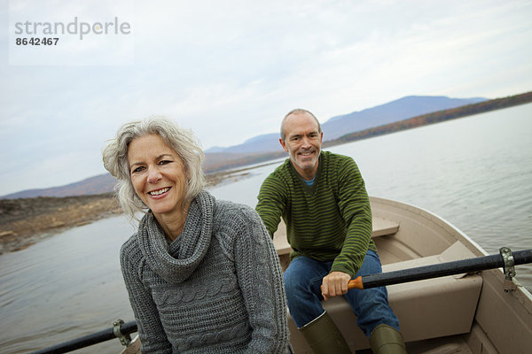 Ein Paar  Mann und Frau  die an einem Herbsttag in einem Ruderboot auf dem Wasser sitzen.