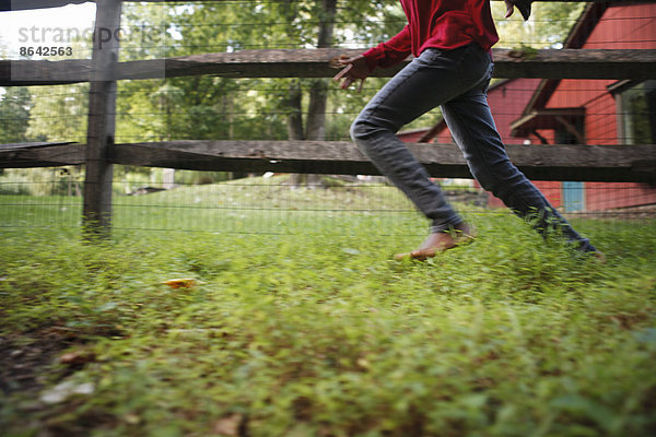 Ein Junge  der im Freien um einen Paddock-Zaun läuft.