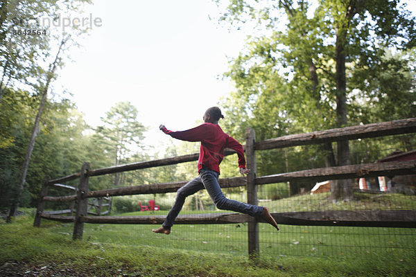 Ein Junge  der im Freien um einen Paddock-Zaun läuft.