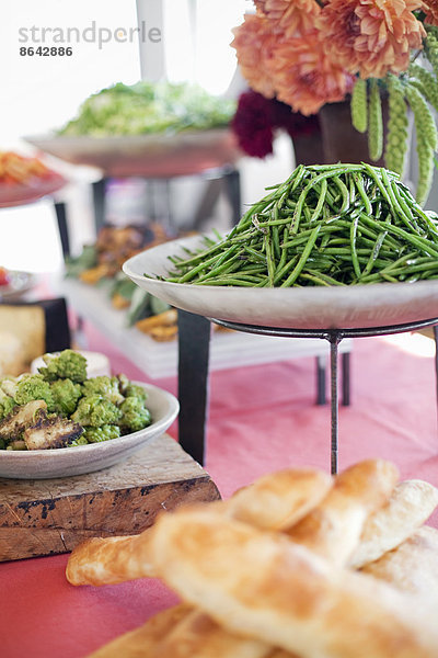 Biologisch zubereitete Salate  Gemüse und Obst auf Gerichten  die für eine Party ausgelegt sind. Ein gedeckter Tisch. Blumen in einer Vase. Ein Imbissstand auf einem Bauernhof.