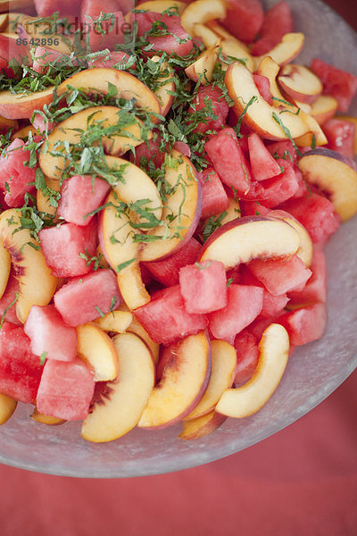 Biologisch zubereitetes Bauernhof-Partyessen. Sommerlicher Obstsalat mit Wassermelone  Pfirsichen und Minze.