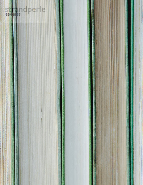 Bücher in einer Reihe  mit grünem Hardcover und weißen und beigen Papierrändern.