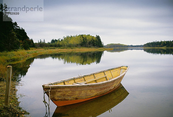 Ein kleines hölzernes Dory oder Ruderboot  vertäut auf flachem  ruhigem Wasser  im Hafen von Savage auf Prince Edward Island in Kanada.