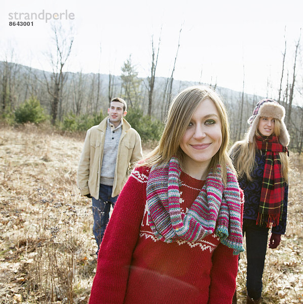 Eine Gruppe von drei Personen  ein Mann und zwei Frauen  bei einem Spaziergang an einem Wintertag.