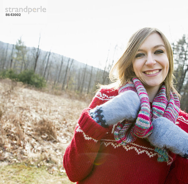 Eine Frau  die an einem Wintertag im Freien einen gestrickten Schal und Wollfäustlinge trägt.