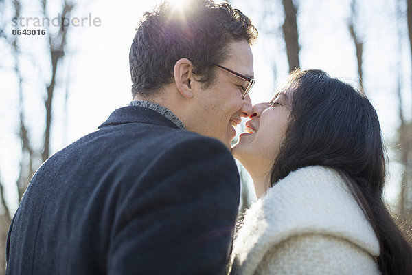 Zwei Menschen  ein Paar  ein Mann und eine Frau an einem Wintertag im Wald. Sie küssen sich.
