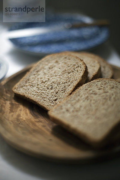 Ein Buffet wird aufgebaut. Geschnittenes Schwarzbrot. Eine blaue Pastete und ein Messer.