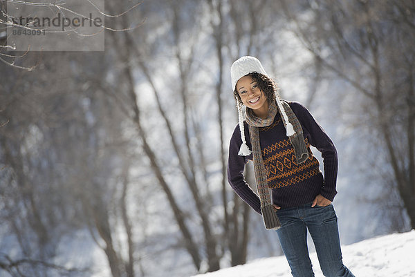 Winterlandschaft mit Schnee auf dem Boden. Eine junge Frau mit Wollmütze.