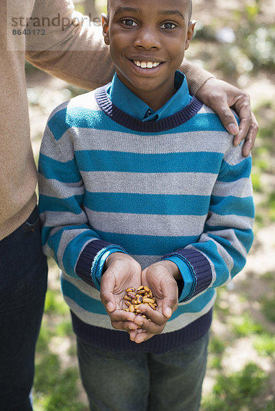 Ein New Yorker Stadtpark im Frühling. Sonnenschein und Kirschblüte. Eine Mutter und ihr Sohn  ein Junge  der eine Handvoll Nüsse hält.