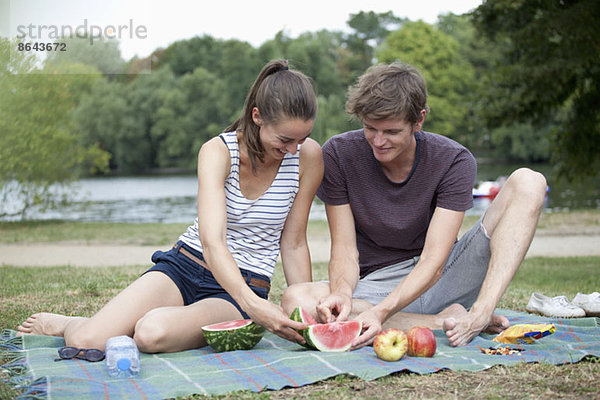 Junges Paar beim Picknick  Wassermelone schneiden