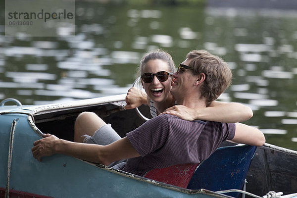 Junges Paar beim Tretbootfahren  lachend