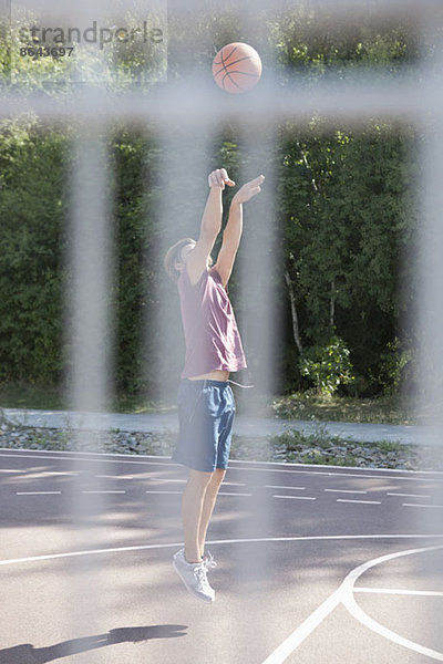 Mittlerer Erwachsener Mann spielt Basketball