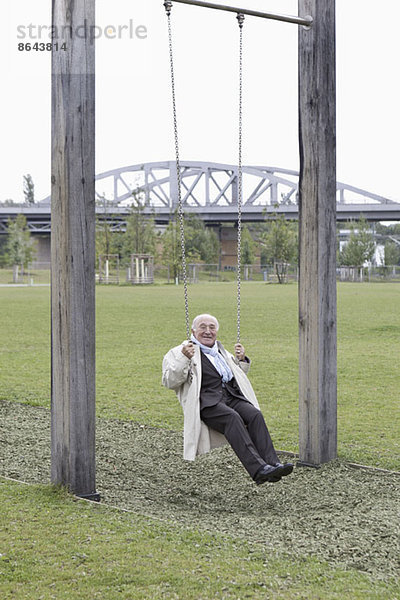 Senior auf Schaukel im Park sitzend